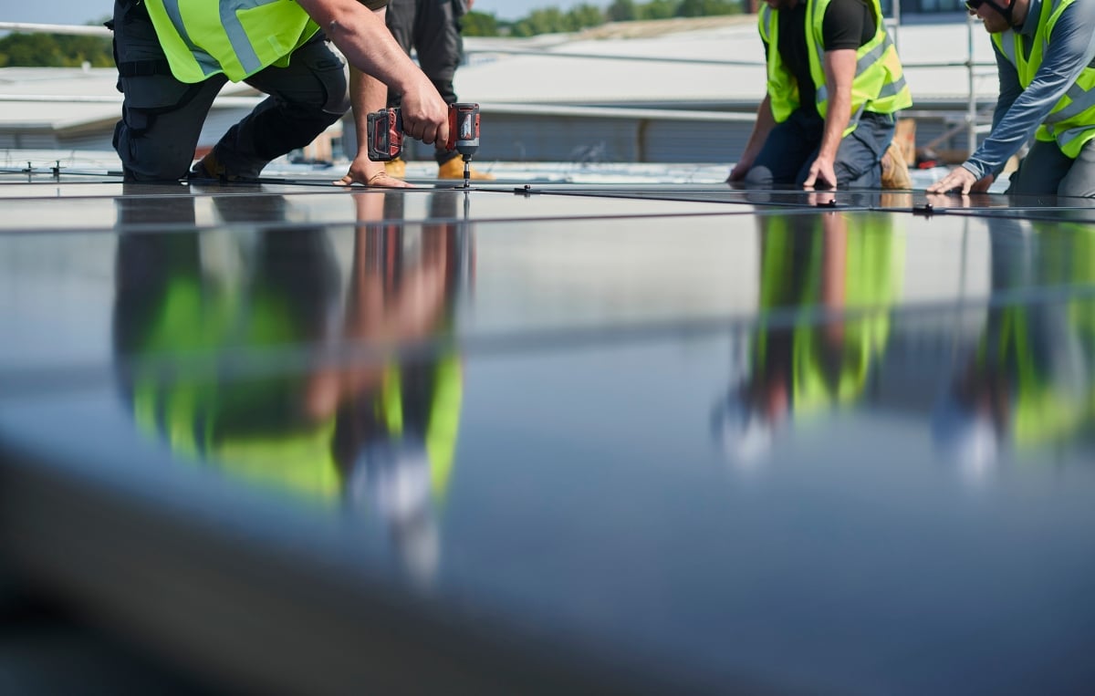 Builders fixing solar panels on a roof