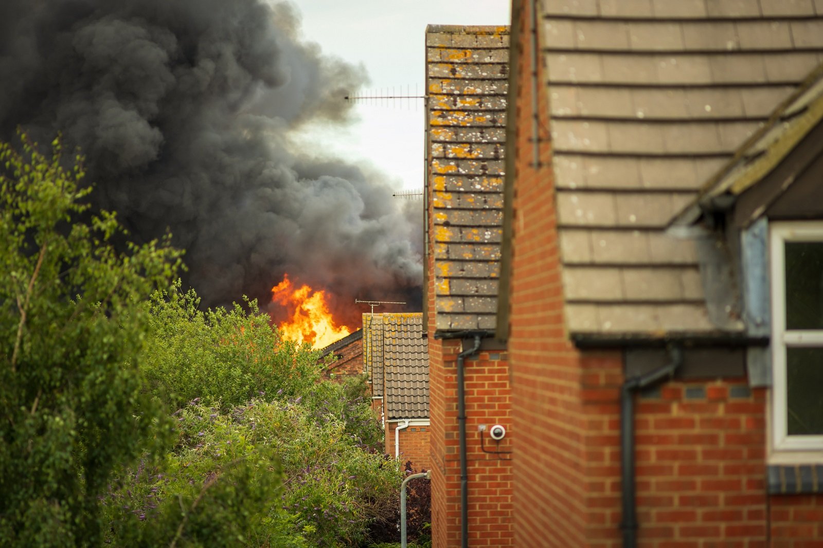 An image showing fire and thick black smoke coming from the roof of a house