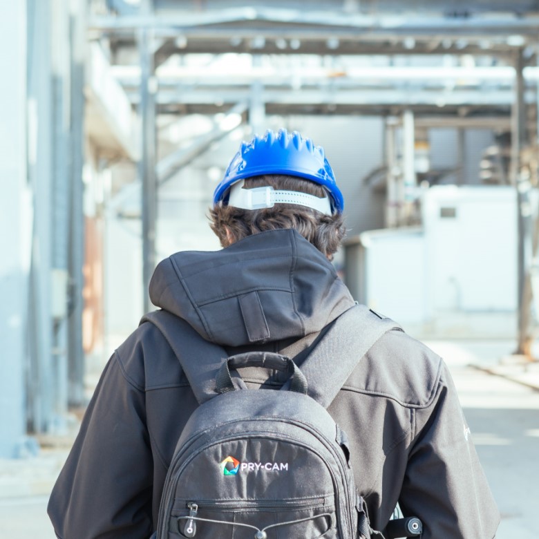 person with pry-cam bag walking through a factory setting.
