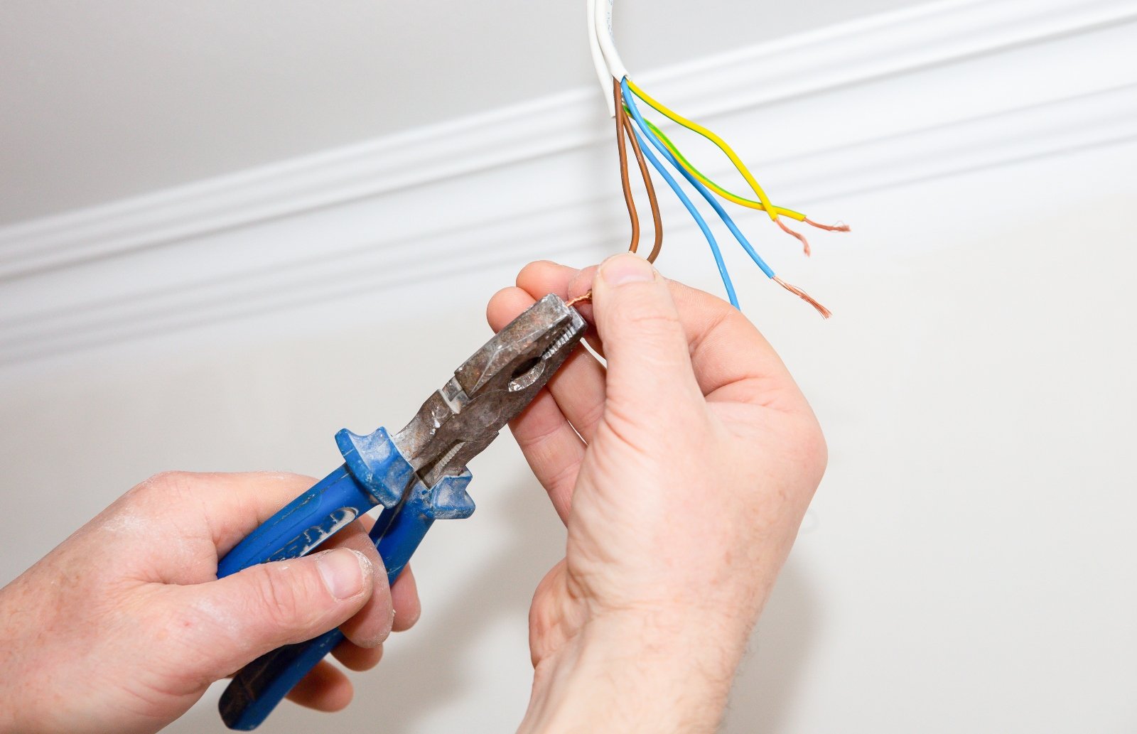 an image showing someone about to cut the wires of a cable dangling from the ceiling