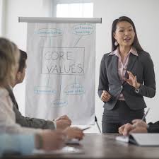 Person dressed in business atire standing next to a whiteboard that says Core Values