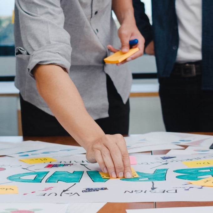 People in an offiice, placing sticky notes on a table