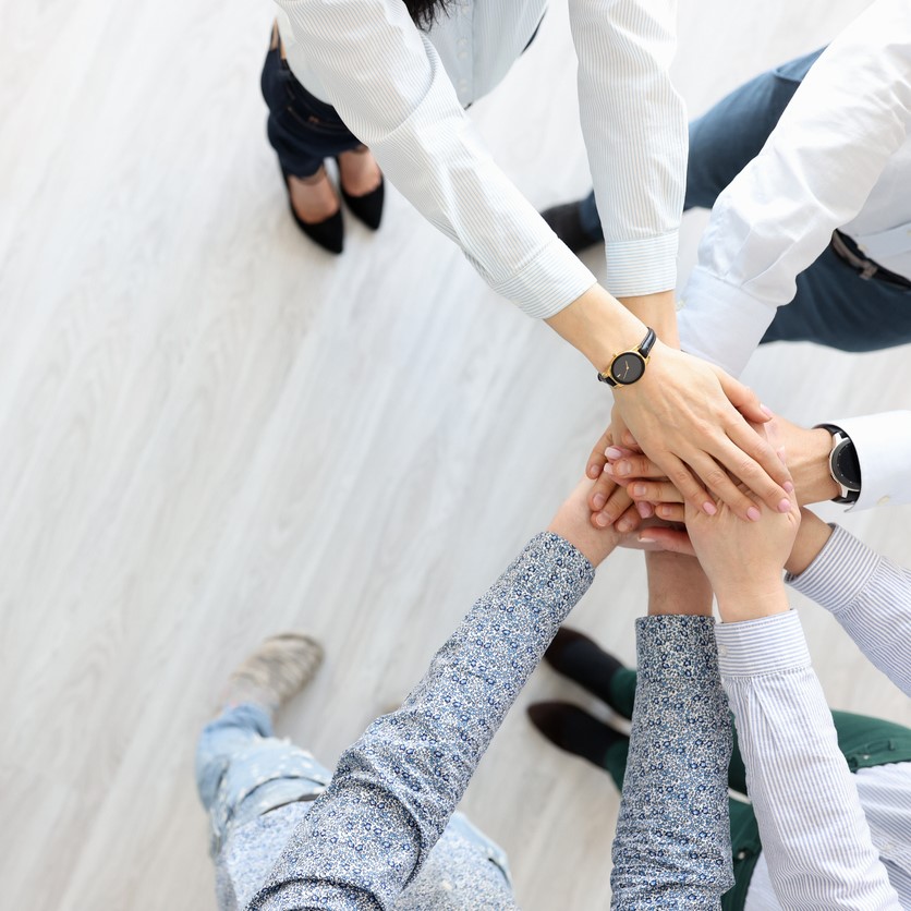 Partners stand and hold their hands in single gesture. Search for business partners concept