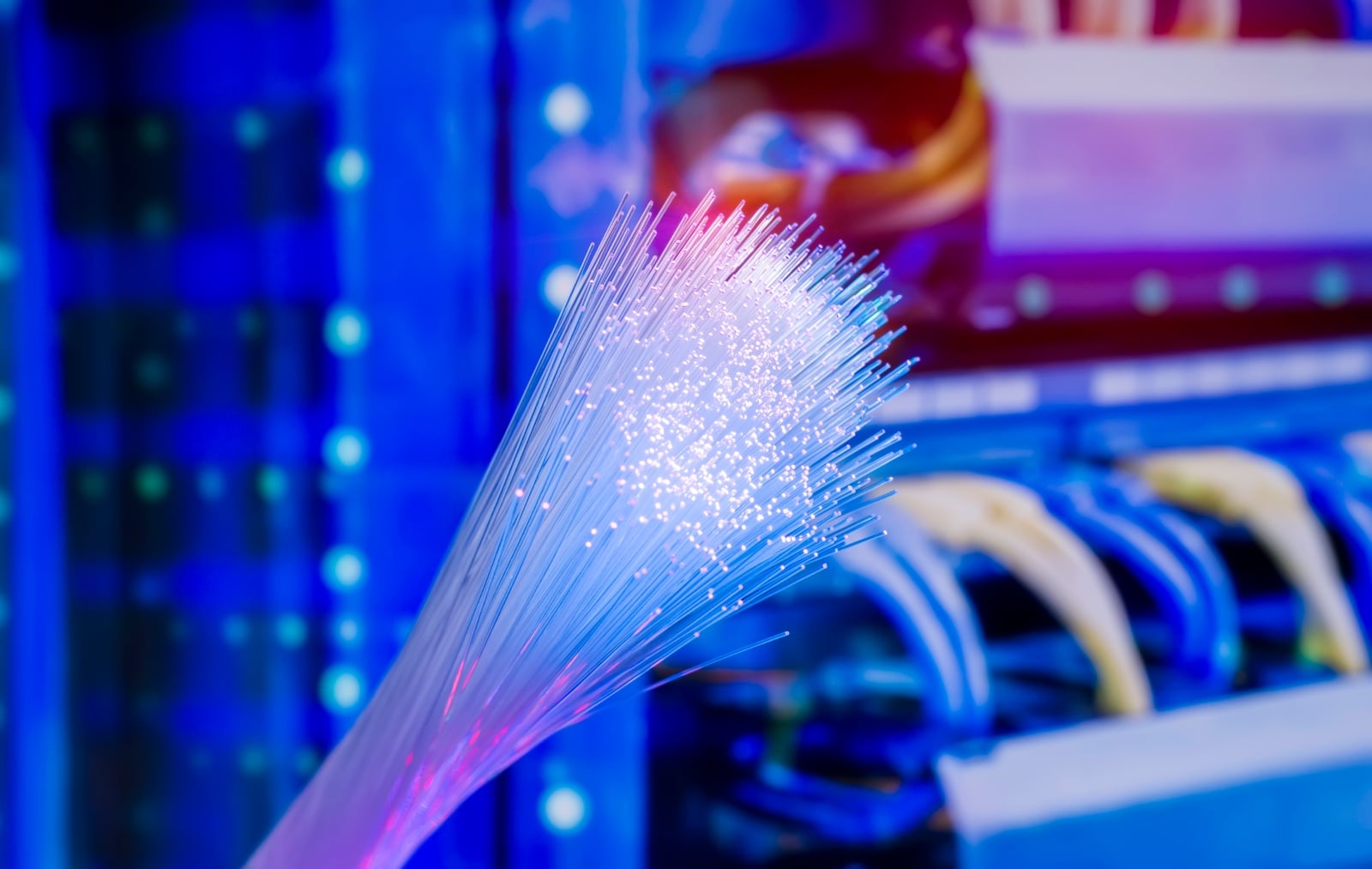 abstract image of fibre optic with a data centre rack in the background
